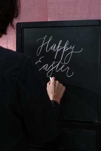 person writing happy easter on chalkboard