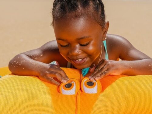 little girl playing on float on beach